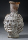 Early Roman deep amber glass Medusa Janus head flask.
