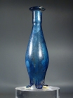 Early Roman blue glass unguentarium (cosmetic flask) with three pinched feet.